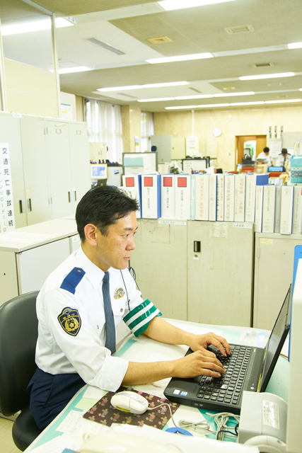 交通課の自分のデスクで仕事をする田中健司警部補